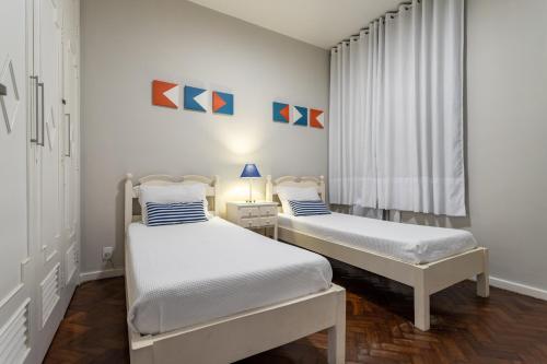 two twin beds in a room with a window at 2 Quartos - Amplo e confortável perto do Metro Flamengo in Rio de Janeiro