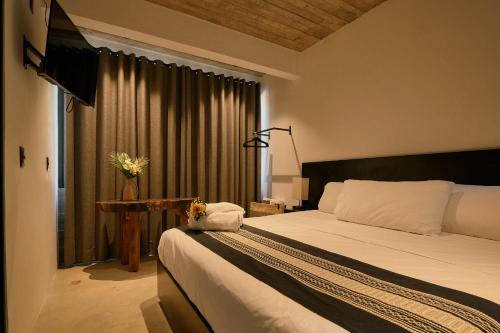 a bedroom with a bed and a table and a window at Aldea Paraíso - Adults only - Boutique hotel in Puerto Escondido