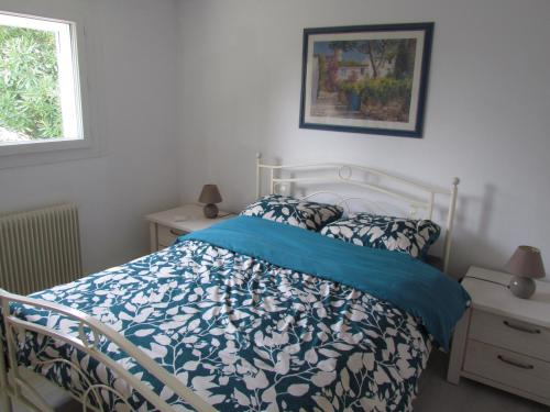 a bedroom with a bed with a blue and white comforter at gîte de la Claveille in Bergerac