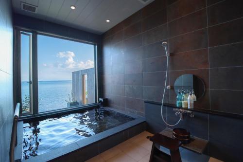 a bathroom with a tub with a view of the ocean at La-se-ri Resort & Stay - Vacation STAY 63385v in Himi