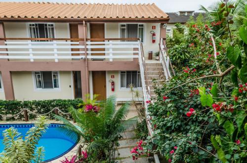 una villa con piscina di fronte a una casa di Pousada Vila da Praia a Bertioga