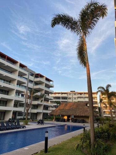 a palm tree in front of a large building at Nuevo Vallarta Lovely 2 bedroom condo pool front in Nuevo Vallarta