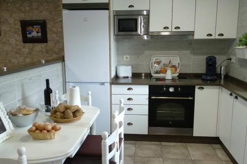 eine Küche mit einem Tisch und einem Herd Top-Backofen in der Unterkunft Casa Rústica Con Encanto. in Brandomil