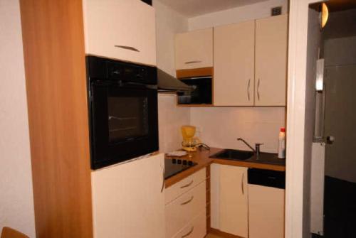 - une petite cuisine avec des armoires blanches et des appareils noirs dans l'établissement Résidence SARRIERE - Studio pour 6 Personnes MAE-8944, à Gourette