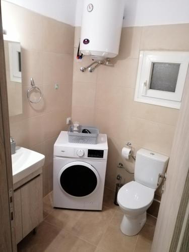 une petite salle de bains avec un lave-linge et des toilettes. dans l'établissement ANIA'S APARTMENT ( ΣΤΟ ΚΕΝΤΡΟ ΤΗΣ ΚΟΖΑΝΗΣ ), à Kozani