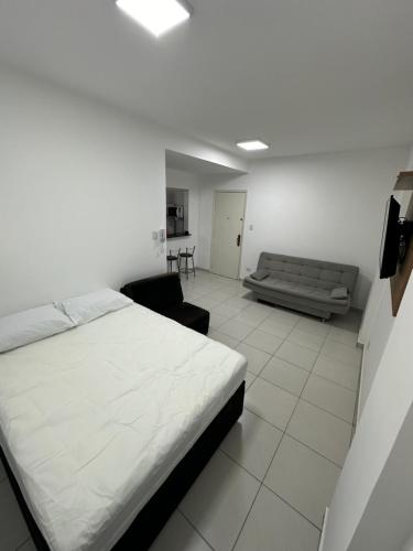 a bedroom with a bed and a couch in it at Kitnet em frente a praia de Santos in Santos