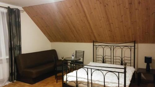 1 dormitorio con cama, sofá y techo de madera en Pensjonacik Zacisze en Pasym