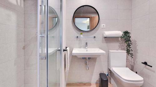 W łazience znajduje się toaleta, umywalka i lustro. w obiekcie Livensa Living Studios Madrid Alcobendas w mieście Alcobendas