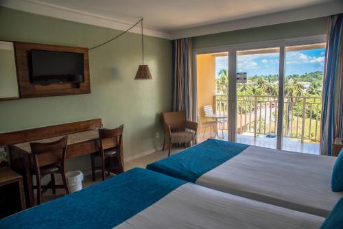 a bedroom with a bed and a desk and a balcony at Gran Hotel Stella Maris Urban Resort & Conventions in Salvador