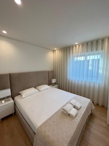 een slaapkamer met een groot bed en 2 handdoeken bij Brittos Home Lovely Stay - Villa Prime in VN de Famalicão Braga in Vila Nova de Famalicão