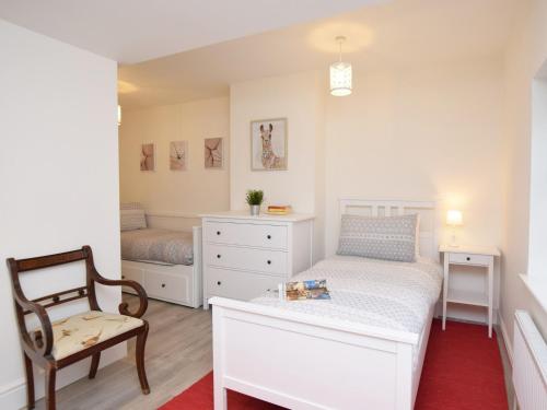 a bedroom with a white bed and a chair at 4 Bed in Corfe Castle 62985 in Worth Matravers