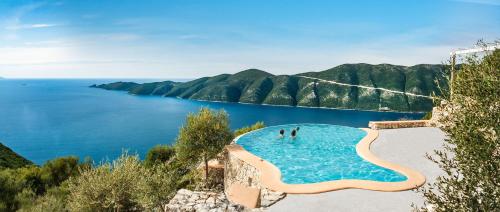 a view of a swimming pool next to a body of water at Heliopetra Luxury Villa Lefkas in Vasiliki