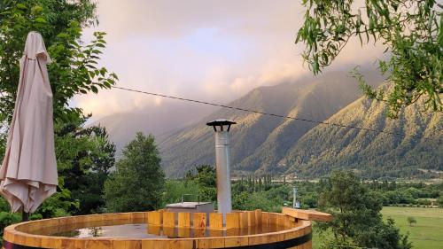 a hot tub with a umbrella and mountains in the background at Cabaña Mirador del Valle in Melipeuco