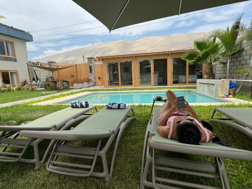 una mujer tendida en sillas de jardín junto a una piscina en Acari Hotel Resort 