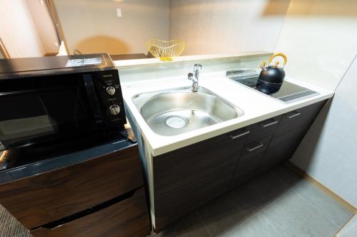 een keuken met een wastafel en een magnetron bij GANADAN Planetarium - Vacation STAY 52396v in Kagoshima