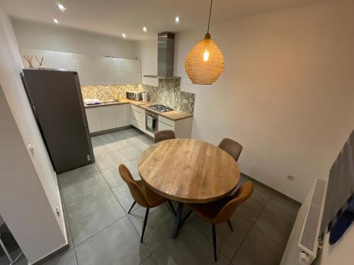 een keuken met een houten tafel en stoelen bij Maison 3 chambres proximité aéroport et grand axes in Charleroi