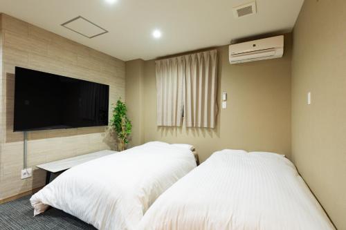 twee bedden in een kamer met een flatscreen-tv bij GANADAN Planetarium - Vacation STAY 52396v in Kagoshima
