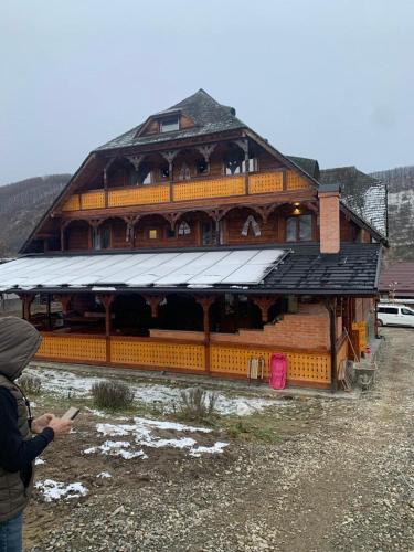 a person taking a picture of a large wooden building at Pensiunea Codrea - Wagner in Lazu Baciului