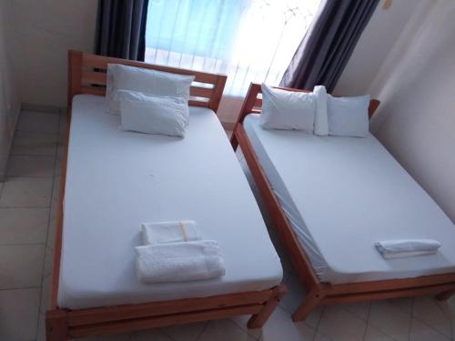 2 bedden in een kamer met witte lakens en kussens bij Two Bedroom Nyali, City Mall in Mombasa