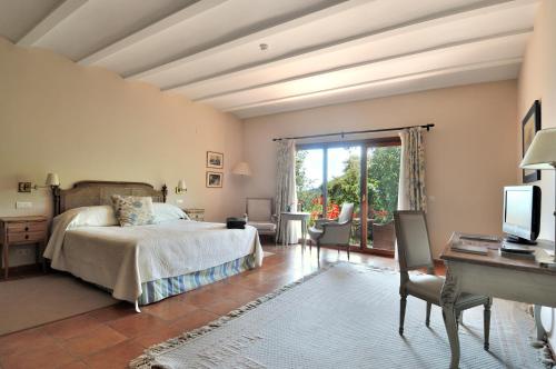a bedroom with a bed and a desk and a television at Finca La Fronda in Alájar
