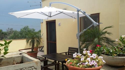 a patio with a bench and an umbrella and flowers at Agriturismo Tenuta La Siesta in Gallipoli