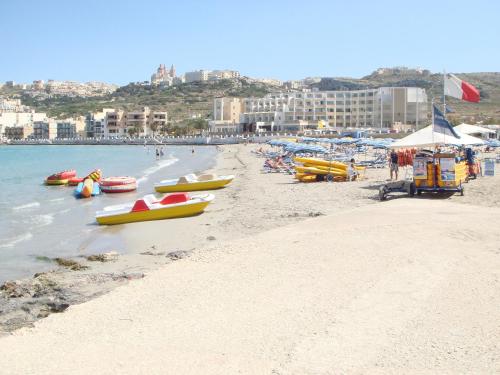 a beach with boats on the sand and buildings at Seafront Maisonette Ocean Views & Terrace in Mellieħa