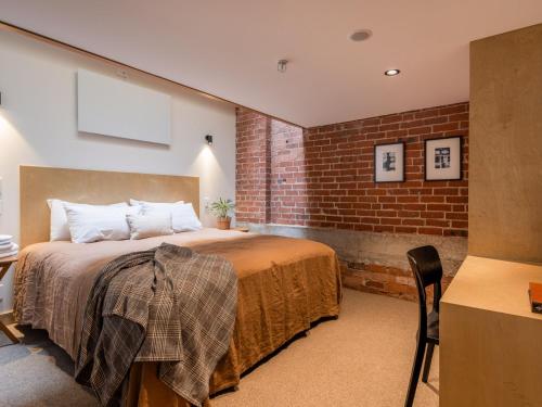 1 dormitorio con cama y pared de ladrillo en The Thomas Gregg Apartments en Dunedin