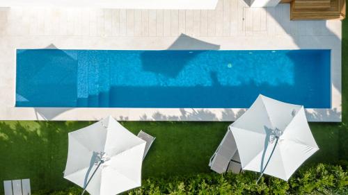 three white umbrellas sitting next to a swimming pool at 5-Star Villa Calma II with Heated Pool & Jacuzzi Oasis in Starigrad-Paklenica