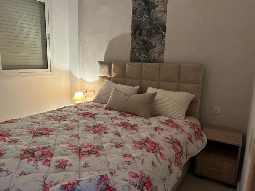 una camera da letto con un grande letto e un piumone floreale di le Lys apprt Oujda a Oujda