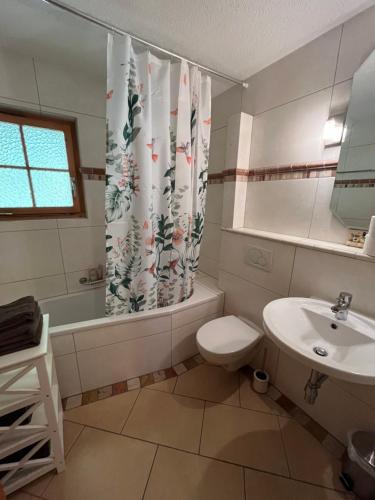 y baño con lavamanos y cortina de ducha. en L'Hérensarde, bel appartement avec jardin-terrasse et garage, en Evolène