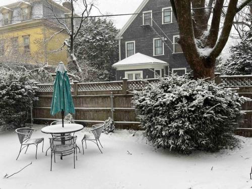 una mesa con sillas y una sombrilla en la nieve en Large Elegant Home Walk to BROWN RISD, en Providence