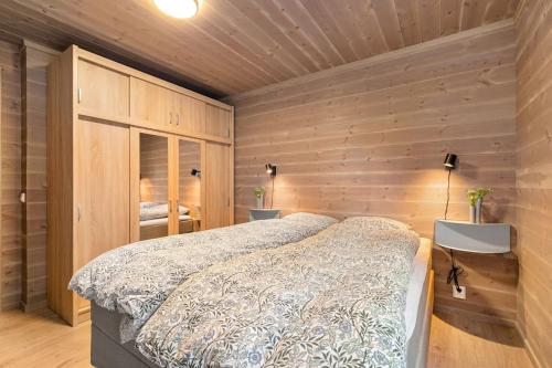 1 dormitorio con 1 cama y pared de madera en Leilighet - Panorama view - Sogndal Skisenter Hodlekve en Sogndal