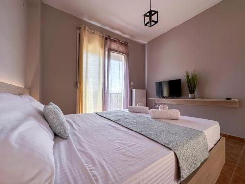 a bedroom with a large white bed with a window at MyseA VillasNikiti in Nikiti