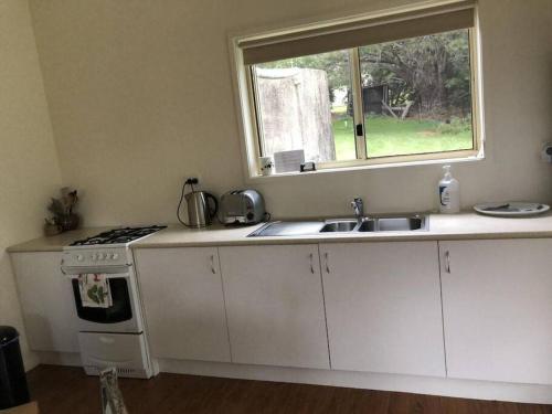 a kitchen with a stove and a sink and a window at Fairmont Cottage in Woodhill