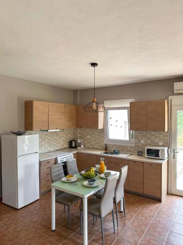 a kitchen with a table and chairs and a white refrigerator at MyseA VillasNikiti in Nikiti