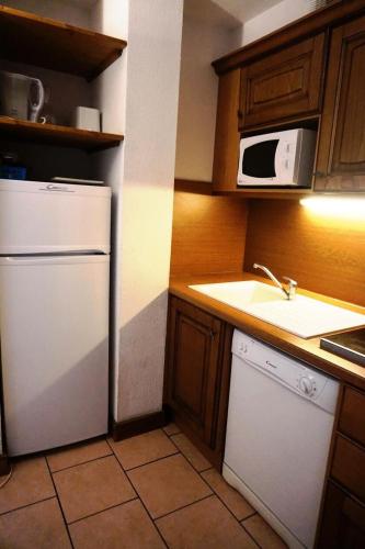 La cuisine est équipée d'un réfrigérateur blanc et d'un four micro-ondes. dans l'établissement Chalet D'orcieres - 2 Pièces duplex 7/8 personnes MAE-2772, à Orcières