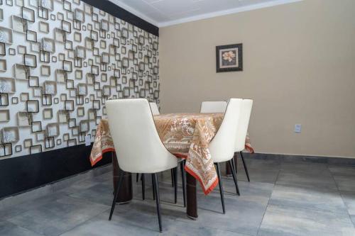 a dining room with a table and white chairs at Casa Magnolia in Tarija