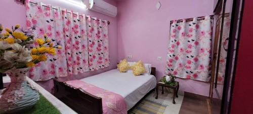 a bedroom with pink walls and a bed with a vase of flowers at Feel the Bong vibes in a villa nearest to airport. in Kolkata