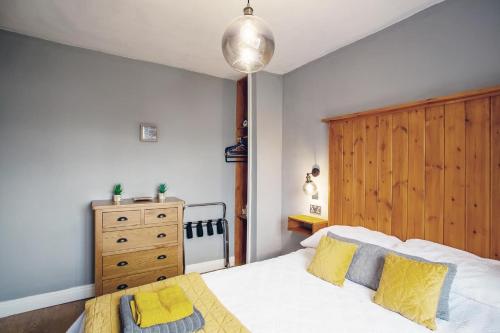 a bedroom with a bed with yellow pillows and a wooden headboard at Stylish 2-Bed Cottage in the heart of Yorkshire in Leeds