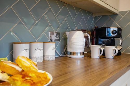 a kitchen counter with coffee cups and a plate of food at Stylish 2-Bed Cottage in the heart of Yorkshire in Leeds