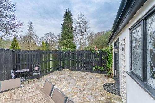 a patio with a fence and a table and chairs at Luxury cosy cottage, enchanting forest location. in Ringwood