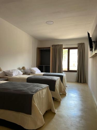 a group of four beds in a room at Hotel Cerros del Norte in Tilcara