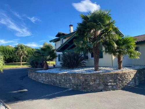 una casa con palmeras y una pared de piedra en Maison basque piscine spa 