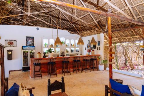 a bar in the middle of a room with stools at Kasha Boutique Hotel in Matemwe