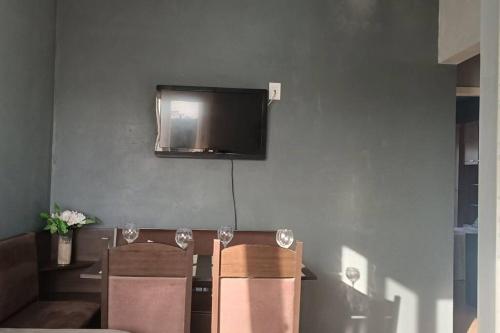 a living room with two chairs and a television on the wall at Sobrado Completo Belíssima in Pelotas