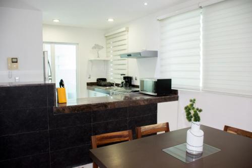 a kitchen with a table with a vase on it at Casa Ohana By Utopia in Playa del Carmen