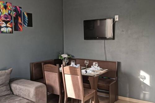 a dining room with a table and a tv at Sobrado Completo Belíssima in Pelotas