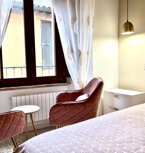 a bedroom with a bed and two chairs and a window at La Chicca di Sofy in Orvieto