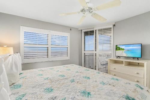 a bedroom with a bed and a tv and windows at Spectacular Gulf Front Condo on the North end of the Island condo in Fort Myers Beach