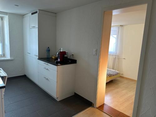 a kitchen with white cabinets and a black counter top at charmante 3,5 Zimmer Wohnung in Bauernhaus in Volketswil